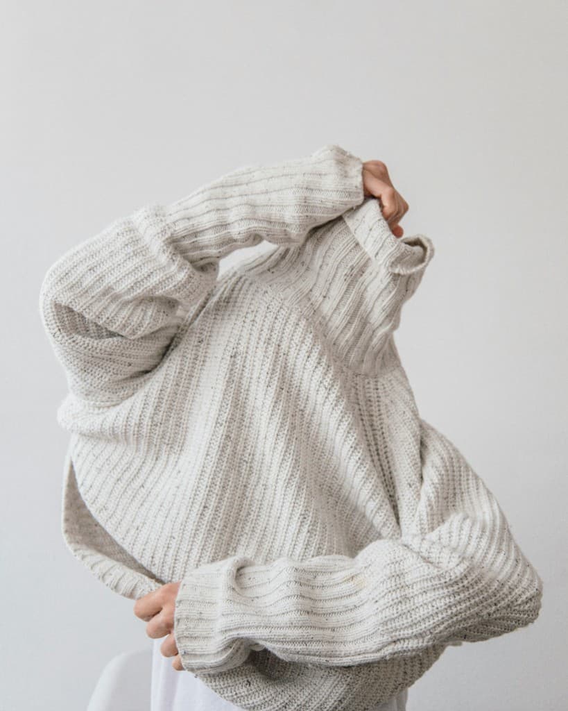 Chunky knit sweater fashion editorial on a gray background